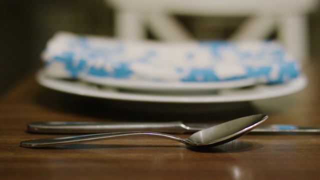 一个白种女人的手把勺子放在木桌上的餐刀旁边视频下载