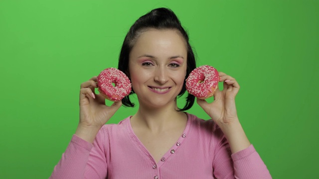 快乐美丽的年轻女孩摆姿势和有乐趣的甜甜圈。色度键视频素材