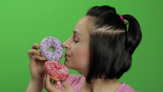 快乐美丽的年轻女孩摆姿势和有乐趣的甜甜圈。色度键视频素材