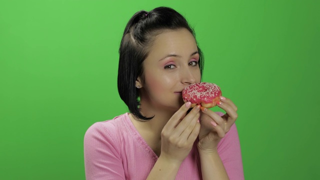 快乐美丽的年轻女孩摆姿势，想要吃一个甜甜圈。色度键视频素材