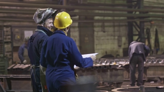 工程师在工厂边走边向焊工展示图纸视频素材