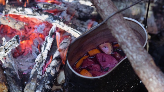 在营火上徒步旅行时，用锅盛着热红酒。视频素材