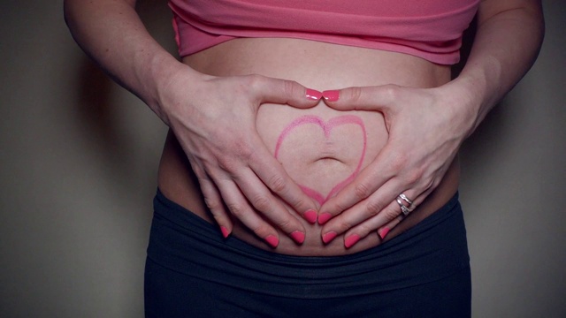 怀孕的肚子上涂着心形口红的妈妈的特写视频视频素材