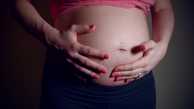 近距离的视频，妈妈轻拍，摩擦和亲吻怀孕的肚子视频素材