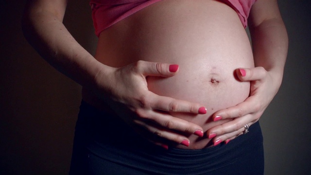 近距离的视频，妈妈轻拍，摩擦和亲吻怀孕的肚子视频素材