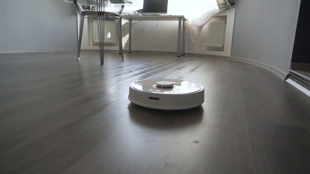 现代的机器人真空吸尘器在打扫起居室的地板视频素材