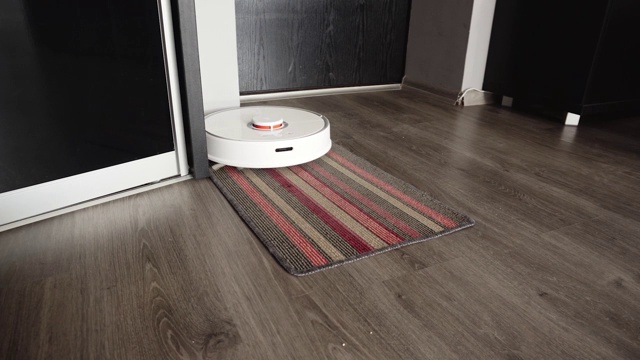 智能机器人吸尘器轻轻清洁走廊的地毯视频素材