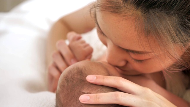 美丽年轻的亚洲母亲与她的新生儿躺在床上在家里视频素材