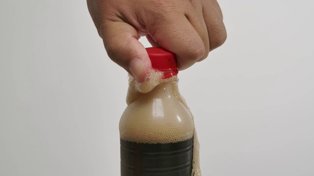 一个男人打开可乐气泡软饮料的瓶盖的特写在白色的背景。视频素材
