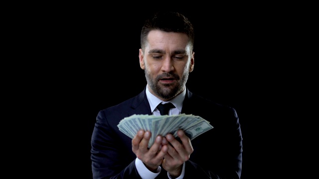 快乐的商人看着手中的美元钞票，财务成就视频素材