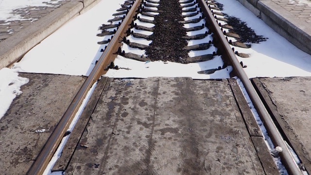 穿过铁路线。空旷的铁路覆盖着积雪，被太阳照亮。视频下载