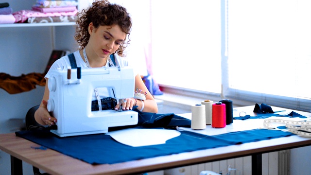 女裁缝在工作室的桌子上用缝纫机工作视频素材