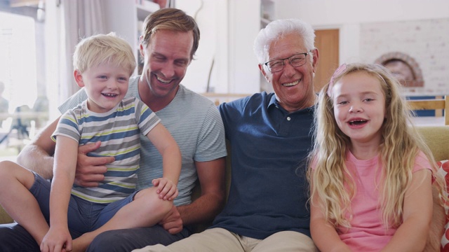 爷爷坐在沙发上，孙子和成年的儿子有说有笑视频素材
