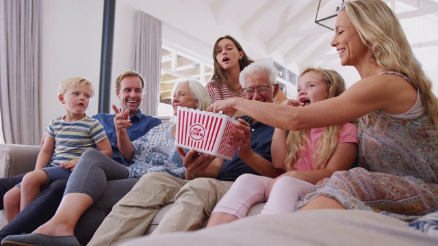几代同堂坐在沙发上一起吃爆米花看电影视频素材