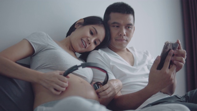一对怀孕夫妇通过耳机给她未出生的宝宝播放音乐视频素材