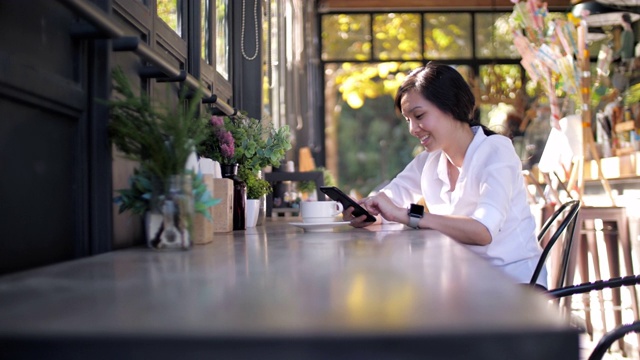 度假的生活方式，女人在咖啡馆用智能手机喝咖啡视频下载