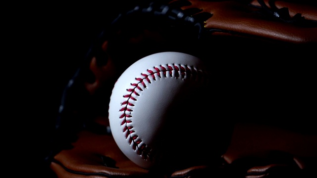 用棒球手套扔棒球，放在黑暗的灯光下视频下载