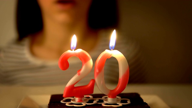 吹灭纸杯蛋糕上20岁生日蜡烛的女孩视频下载