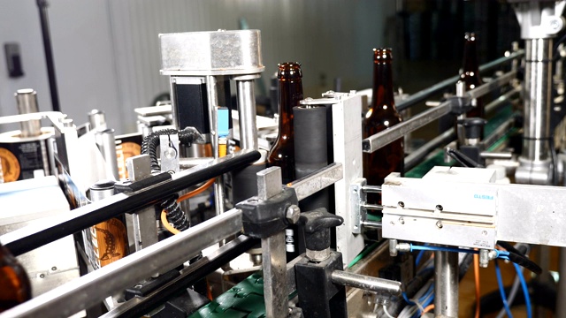 在啤酒厂的技术生产线上，空瓶子排成一排。玻璃瓶厂传送带上的瓶子。4k视频素材