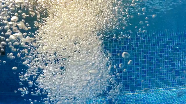 气泡浮到水面。缓慢的运动。气泡在清澈的蓝色水中(水下拍摄)，很好的背景视频素材