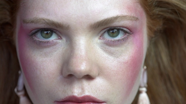 一个年轻女人的脸的特写，红头发和蓝绿色的眼睛。视频下载