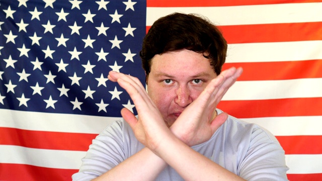 一名男子双手交叉，在美国国旗的背景上做停止手势视频下载