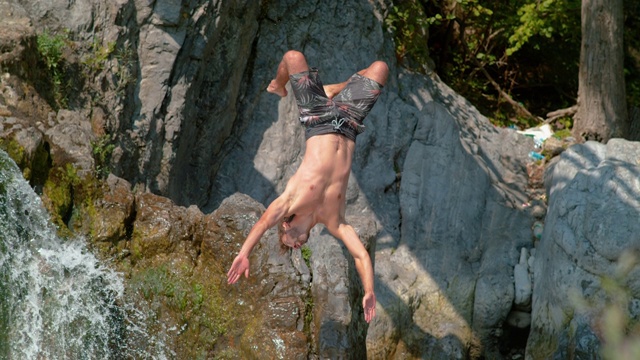 慢镜头:一个运动员从瀑布上做后空翻的惊险镜头视频下载