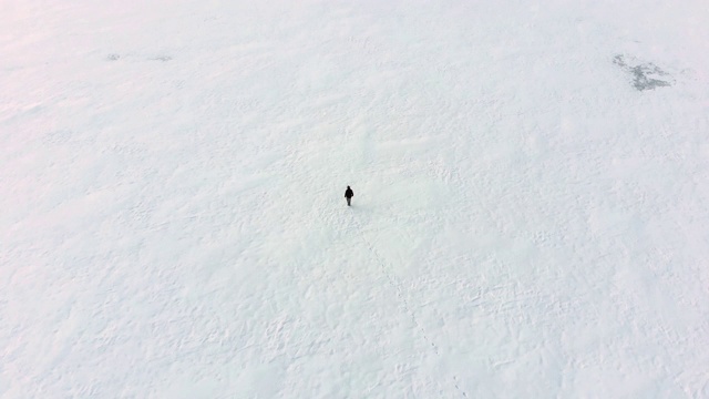 一个人走在雪地上的空中盘旋镜头。视频下载