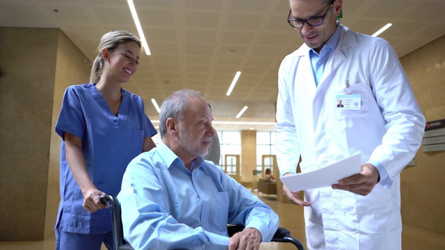 医生向坐在轮椅上的老病人问好，同时向他展示医院的一些测试结果视频素材