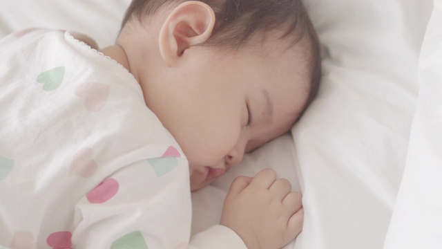 8个月大的女婴睡在家里白色的床上视频下载