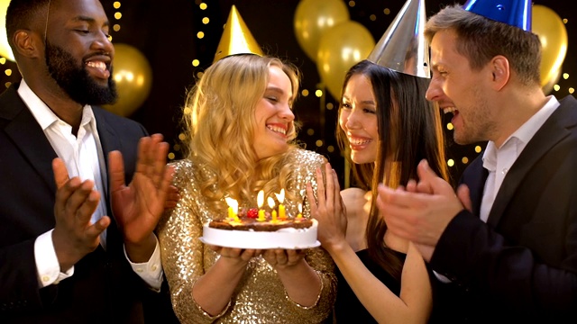 快乐的金发女人吹蛋糕蜡烛，朋友祝贺女人生日视频下载