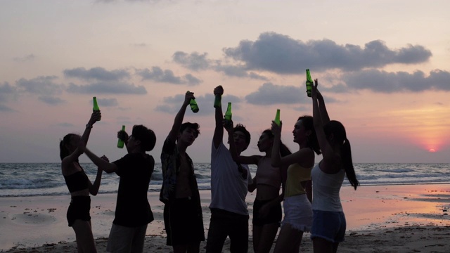 剪影亚洲青少年群舞和饮料一起在海滩夏季日落背景。年轻的亚洲快乐的情感和周年庆典。4K分辨率和慢镜头。视频素材