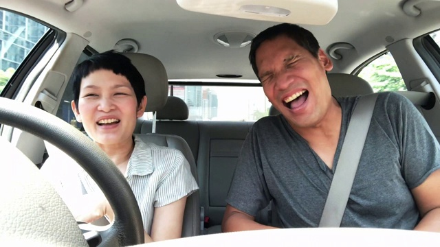 成熟的亚洲夫妇在车里谈笑风生。亚洲的中年朋友喜欢在开车的时候交谈视频素材