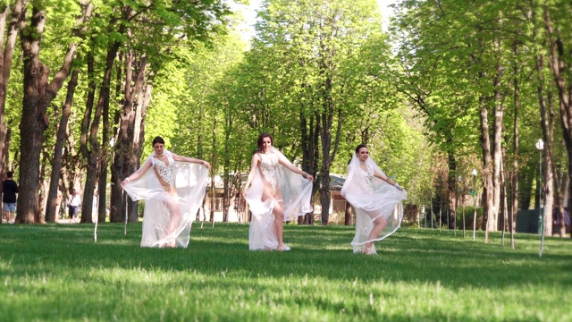 穿着性感服装和新娘面纱的女舞者在绿色公园跳舞视频下载
