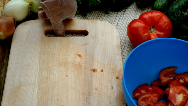 人的手切红多汁的西红柿，用于烹饪蔬菜沙拉在木板上。视频下载