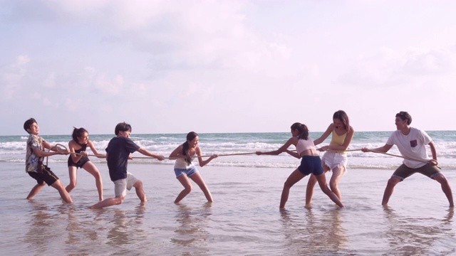 一群朋友在沙滩上玩绳子玩得很开心。视频下载