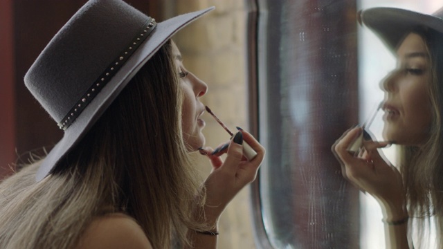 在奥斯汀酒吧的镜子里，时髦的年轻女子用唇刷补妆。视频下载