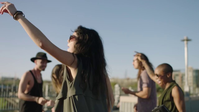 无忧无虑的年轻女子欢呼，她与朋友在Pfluger人行天桥上疯狂地跳舞，奥斯汀市中心的天际线为背景。视频下载