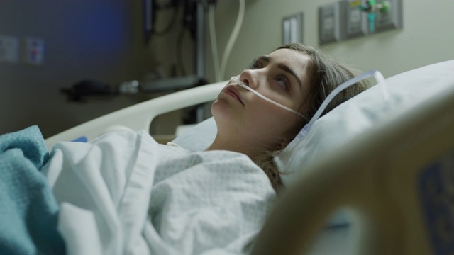 美国犹他州盐湖城，一个不开心的女孩躺在医院的病床上，鼻子里插着呼吸管视频素材