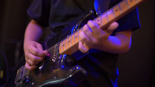 吉他手摇滚明星在乐队舞台上弹奏吉他的细节。视频下载