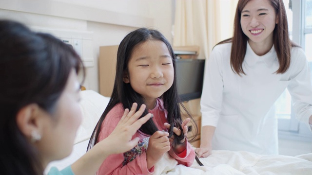 近距离拍摄生病的小女孩在病床上与母亲和护士视频素材