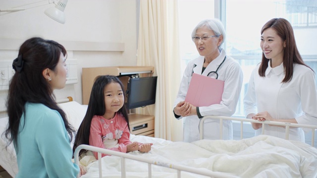 母亲和小女孩在医院与儿科医生和护士交谈视频素材