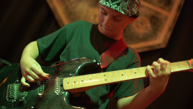 一个音乐家吉他手摇滚明星青少年在一个摇滚乐队的舞台上弹吉他。——慢动作视频下载
