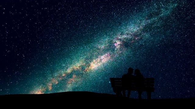 男人和女人坐在长椅上，背景是星空。时间流逝视频素材