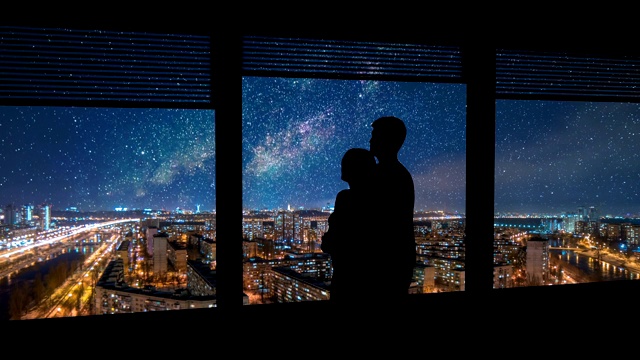 这对情侣站在窗前，满天繁星，俯瞰着城市风光。时间流逝视频素材