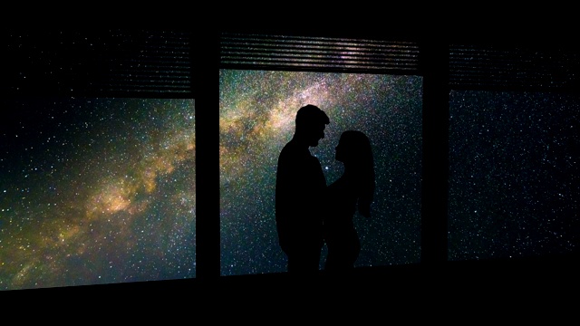 一个男人和一个女人站在窗前，星空背景。时间流逝视频素材