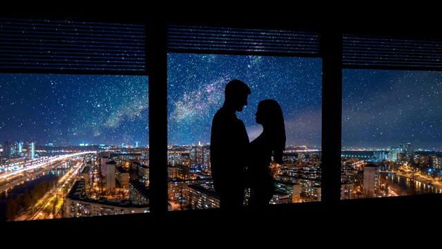 一男一女站在窗前，背景是夜晚的城市视频素材