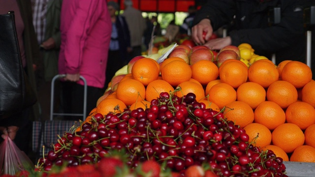 人们在水果和蔬菜市场，一个小贩把她的货物放在桌子上视频下载