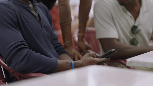 年轻的非裔美国朋友聚在奥斯汀时髦的酒吧里看智能手机。视频素材