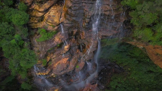 空中倾斜:美丽的瀑布在令人惊叹的悬崖墙上郁郁葱葱的绿色，蓝山，澳大利亚视频素材